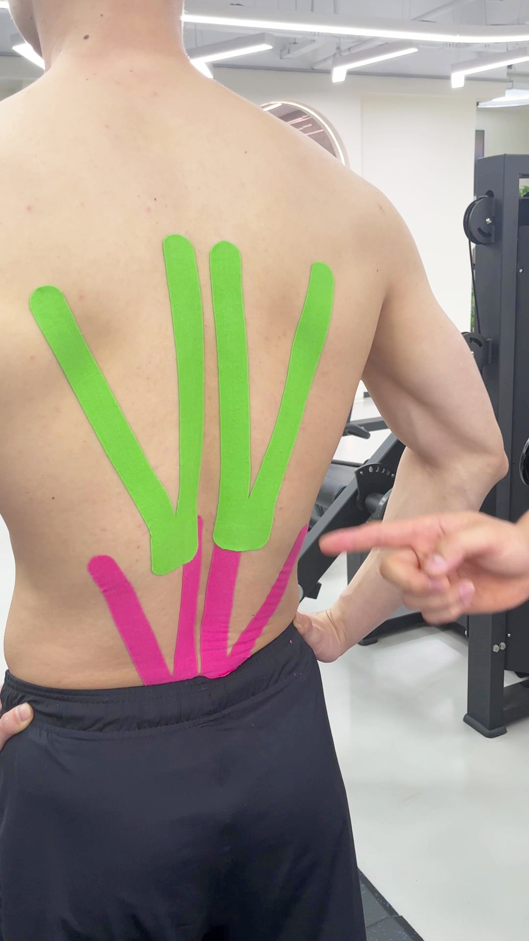 {"default":"Applying pink and green cotton kinesiology tape for support for full back"}
