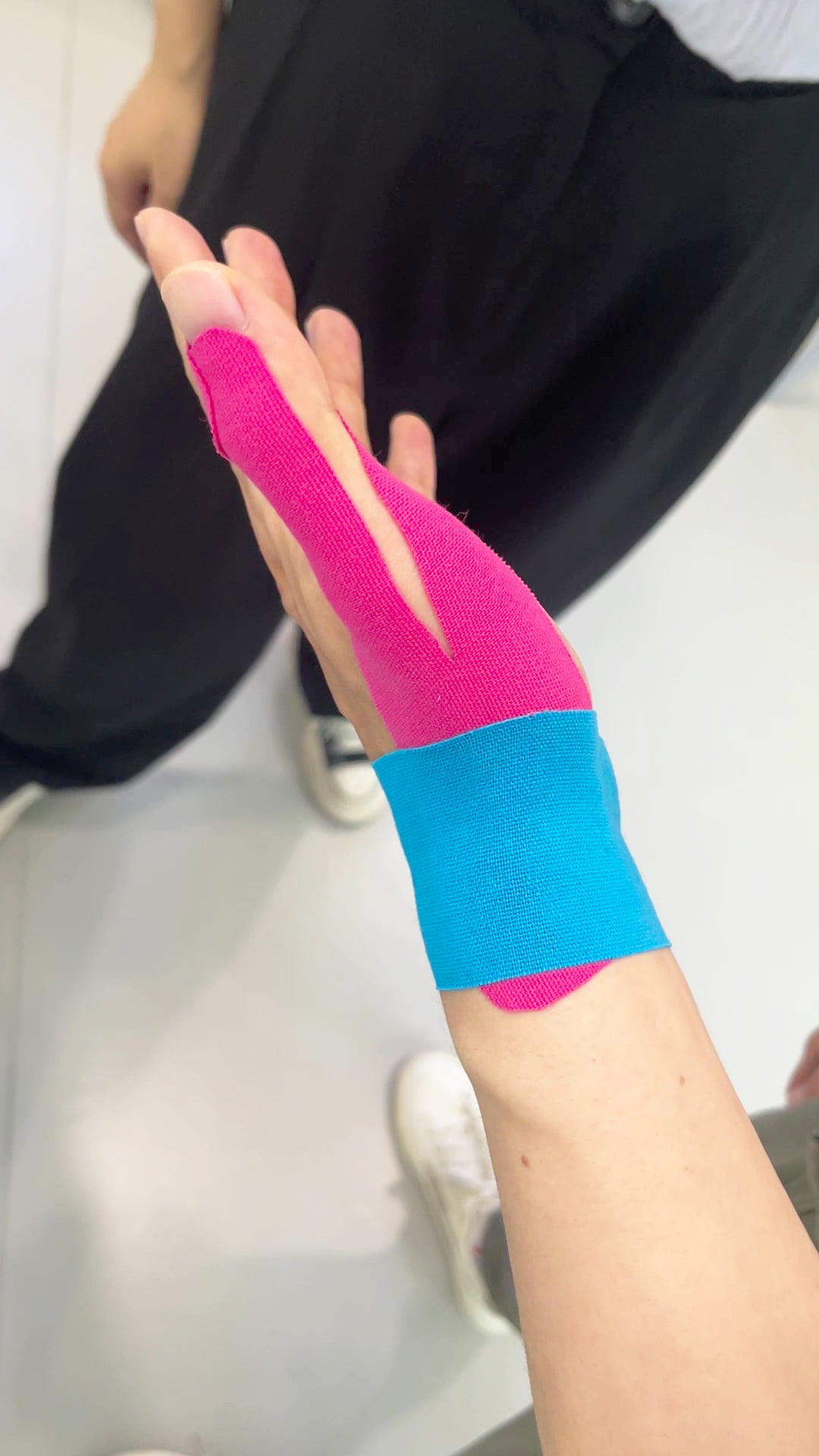 {"default":"Applying blue and pink cotton kinesiology tape on wrist for support"}
